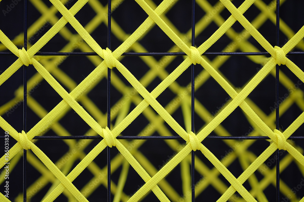 Yellow rope tied to a black steel grill, Abstract texture background Yellow rope tied to a black steel grill, Abstract texture background