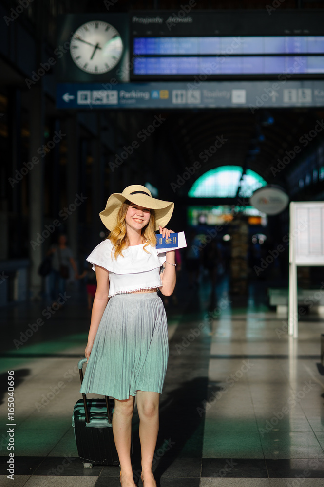 Fototapeta premium Charming girl in sun-hat in the waiting room of the train station.