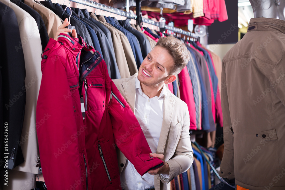 Obraz premium Cheerful male customer examining coats