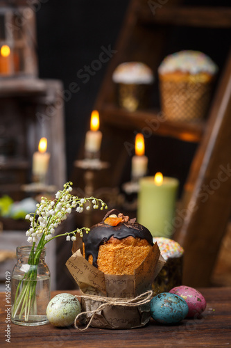 Festive cupcake with a bouquet of valley lilies on a background of candles