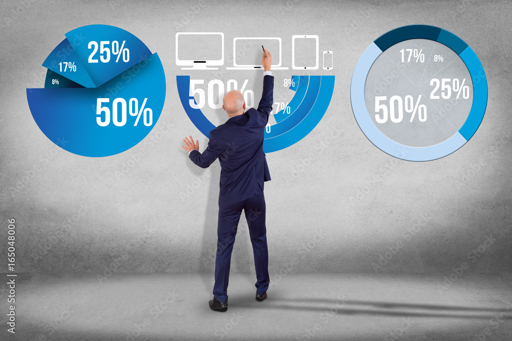 Businessman in front of a wall writing on a statistics interface - business concept Businessman in front of a wall writing on a statistics interface - business concept