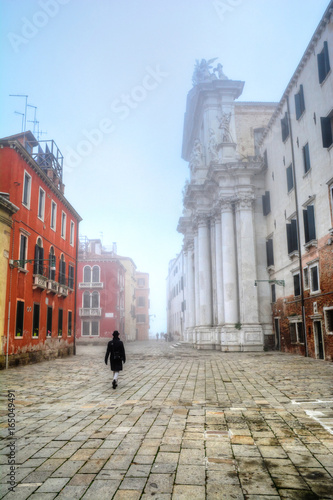 One person walking alone among traditional architecture in Venice in a fogy weather