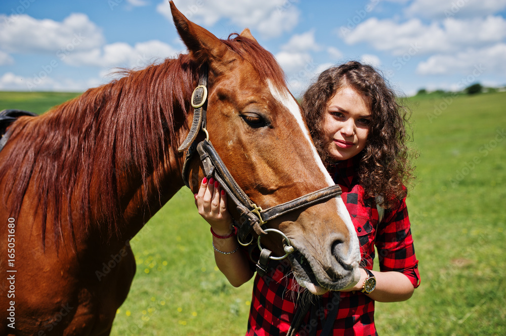 Obraz premium Young pretty girl stay with horse on a field at sunny day.