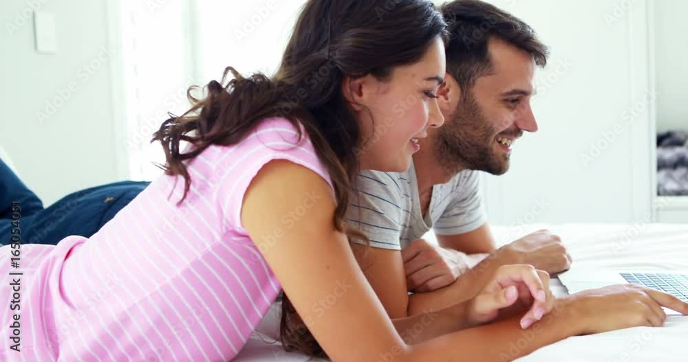 Couple interacting with each other while using laptop on bed Couple interacting with each other while using laptop on bed