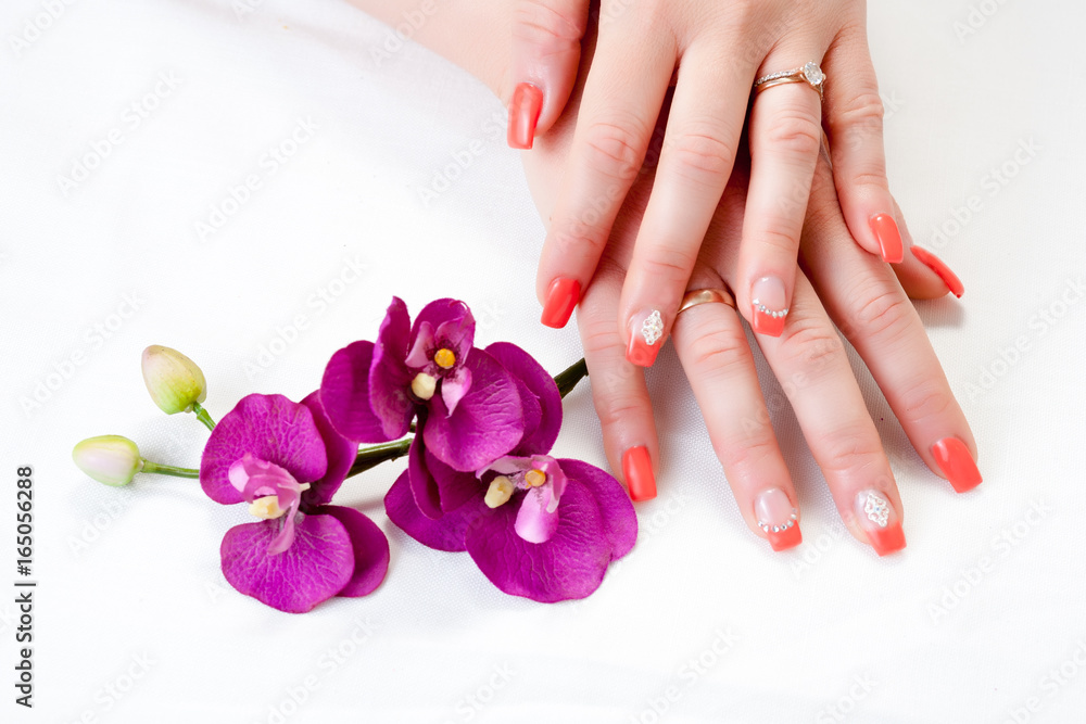 female hands with orchid petals and nail art
