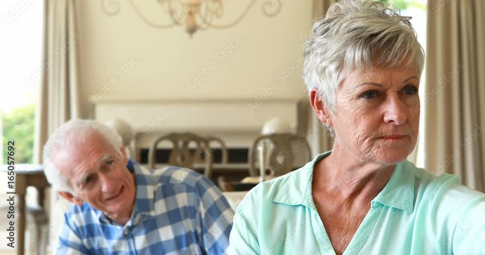 Senior couple arguing with each other in the living room Senior couple arguing with each other in the living room
