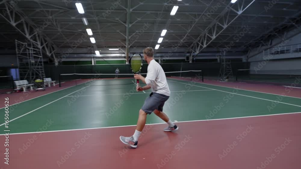 Unrecognizable male sportsman holding racket and playing tennis on court Unrecognizable male sportsman holding racket and playing tennis on court