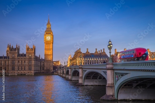 London, England - The iconic Big Ben with Houses of Parliament and traditional red double decker bus on Westminster Bridge at sunrise with clear blue sky