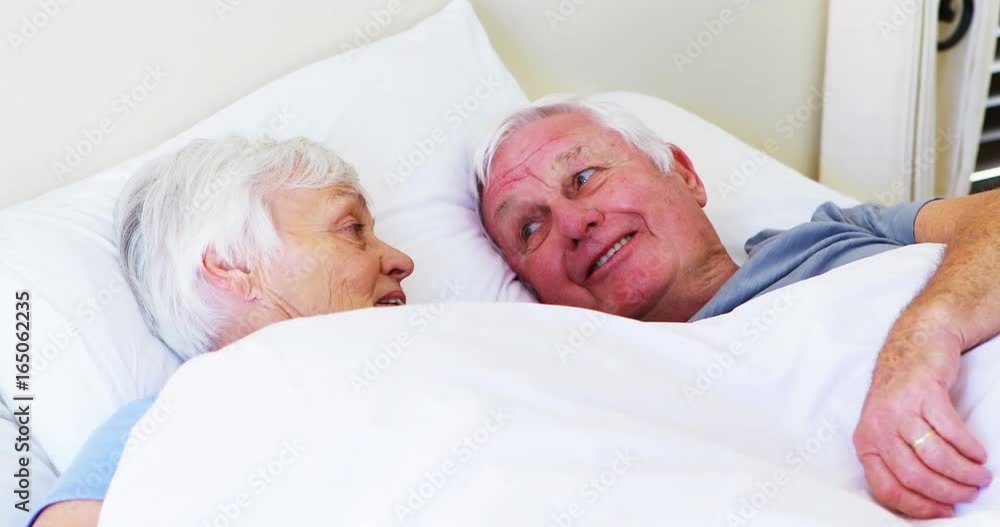 Happy senior couple interacting with each other while lying on bed 