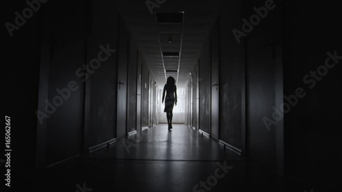 Wallpaper Mural Tilt up of silhouette of unrecognizable businesswoman walking elegantly along dark corridor towards camera  Torontodigital.ca