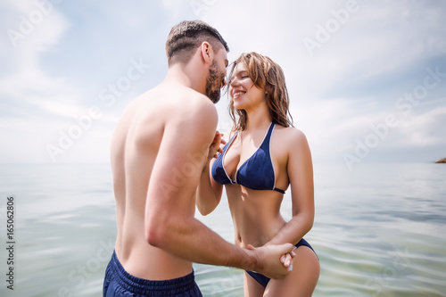 Sexy couple at sea,slim body,long hair,swimwear,swimsuit,beautiful tan,summer holidays concept,make up,bearded man