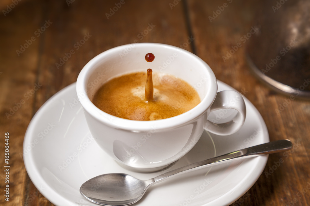 Coffee drop in espresso cup on old wooden table. Coffee drop in espresso cup on old wooden table.