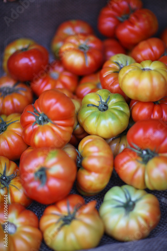 Large tomatoes of different degree of maturity in a box on the counter of the agricultural market