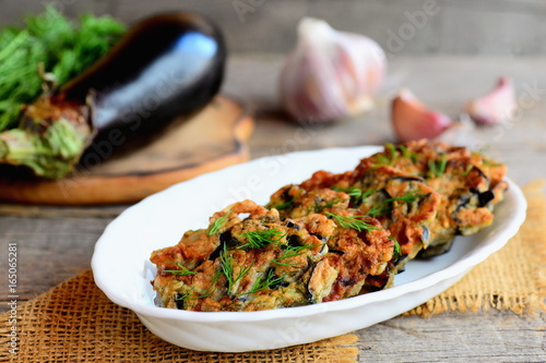 Vegan fried eggplant cutlets with garlic and dill on a white plate and a vintage wooden table. Gluten-free eggplant cutlets idea. Closeup