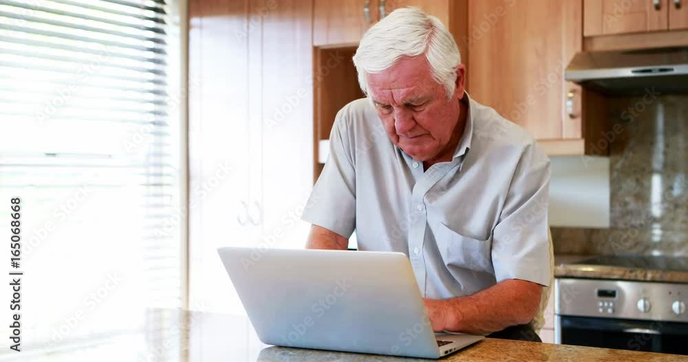 Senior man using laptop in the kitchen Senior man using laptop in the kitchen