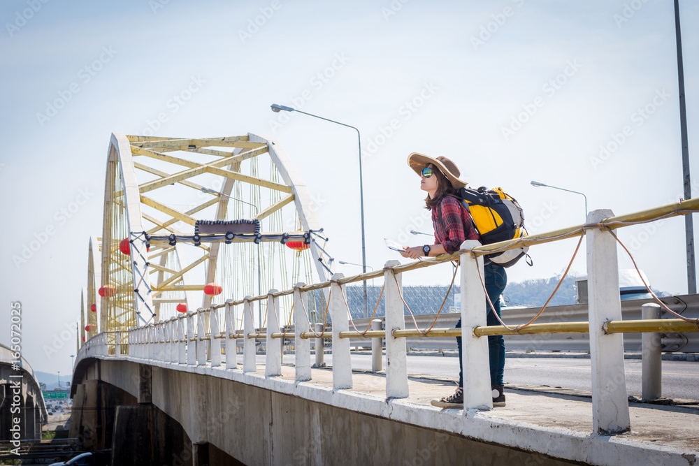 Girl tourists read the map on the bridge.