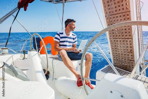 Man with laptop computer on sailboat