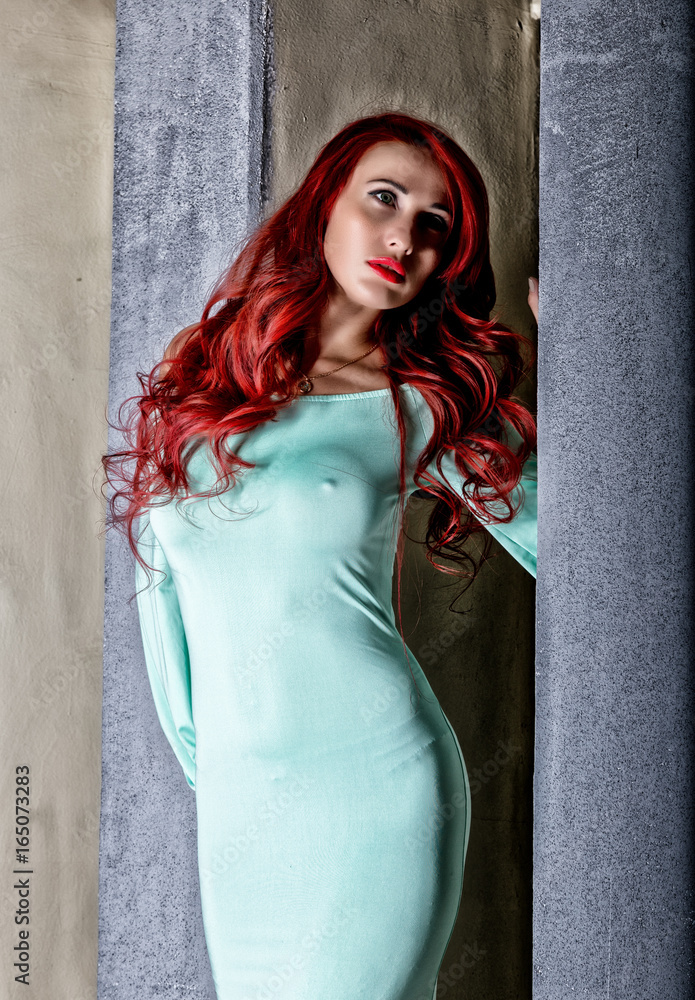 sexy beautiful redhead young woman with big boobs in a turquoise dress on a  old gray wall background Stock-Foto | Adobe Stock