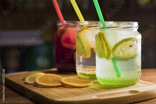 Three glasses of different flavored lemonades on the counter served in jars
