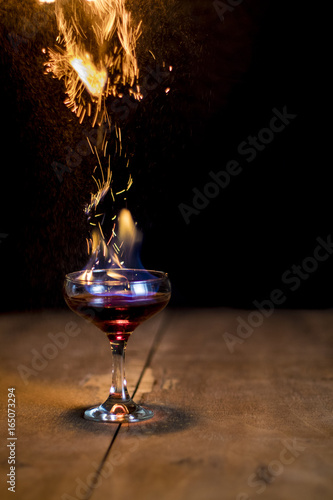 Glass of flaming cocktail with sparks of buring cinnamon (flaming lamborghini)