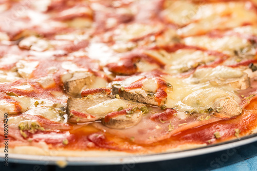 Closeup macro fresh baked round pizza with cheese ham tomato sauce mushrooms