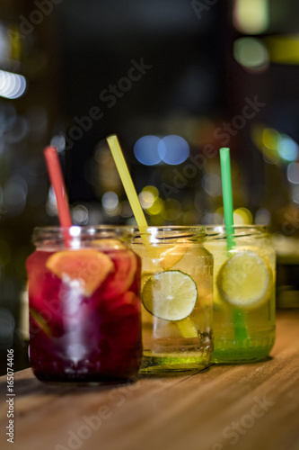 Three glasses of different flavored lemonades on the counter served in jars
