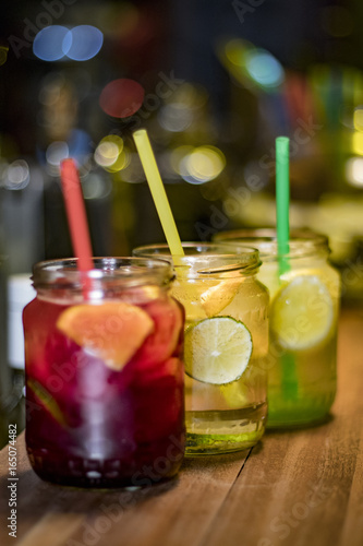 Three glasses of different flavored lemonades on the counter served in jars