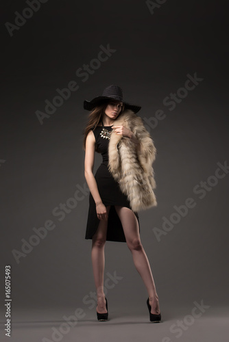 Beautiful, glamorous girl, model in a beautiful evening dress, decoration, outer clothing and hat. Fashion, style, beauty, lifestyle, studio.