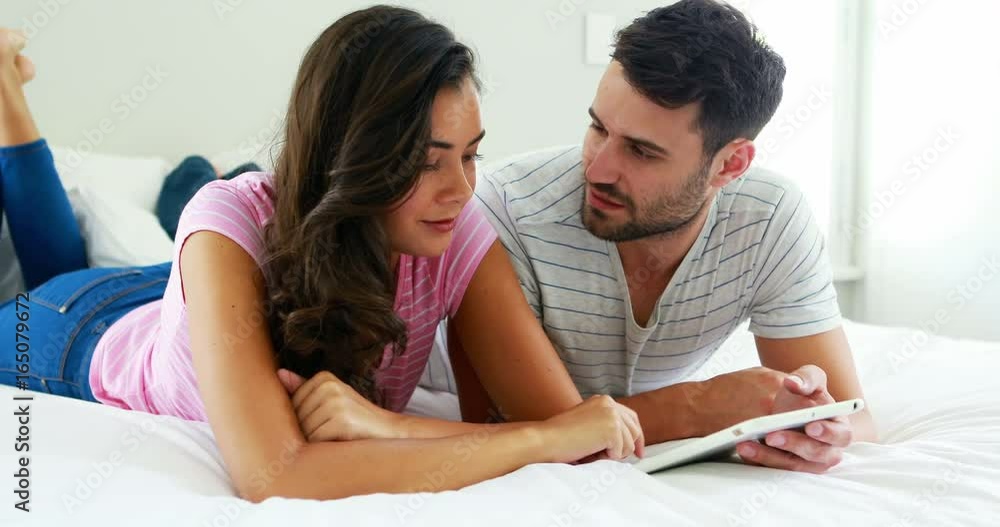 Couple interacting with each other while using digital tablet in the bedroom Couple interacting with each other while using digital tablet in the bedroom