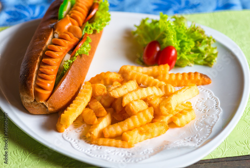 Fast food is nicely served on a plate hot dog and potatoes with vegetables
