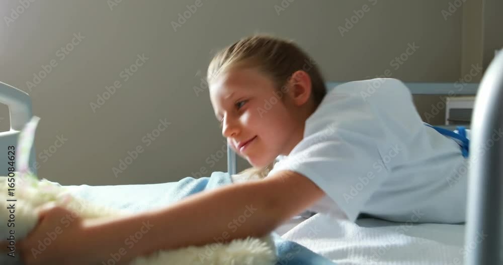 Sick girl playing with teddy bear on bed Sick girl playing with teddy bear on bed