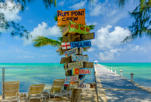 Colorful signpost by the Caribbean sea and a jetty at Rum Point, Grand Cayman, Cayman Islands