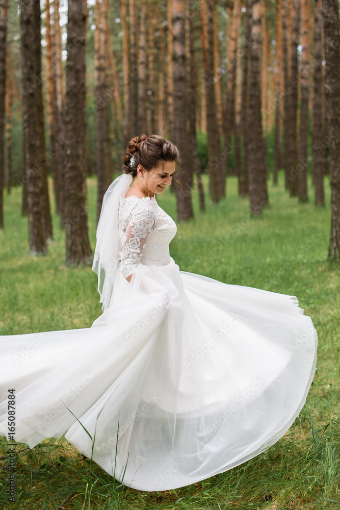 Handsome gorgeous bride in white wedding dress dancing in the forest in nature