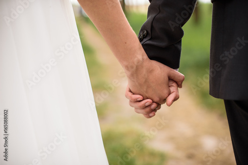 Bride and groom walking and holding hands in the forest on nature