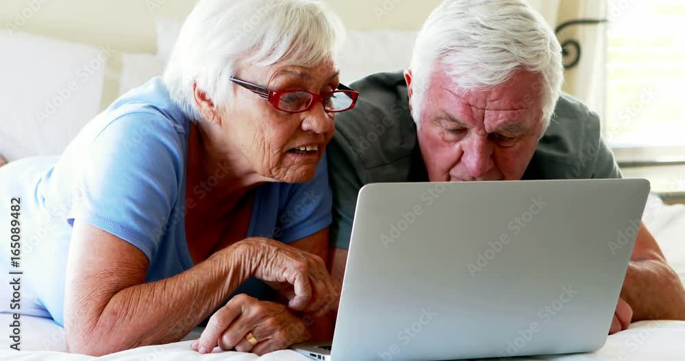 Couple lying on bed and using laptop Couple lying on bed and using laptop