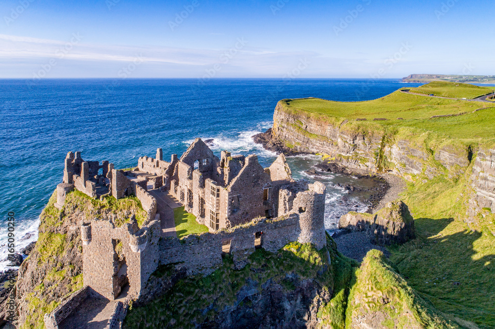 Ruins of medieval Dunluce Castle, cliffs, bays and peninsulas. Northern coast of County Antrim, Northern Ireland, UK. Aerial view.