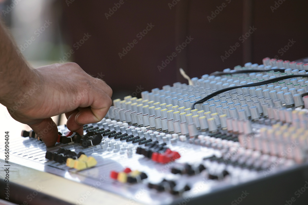 Fototapeta premium A sound mixer with the operator's hand changing the potentiometer setting