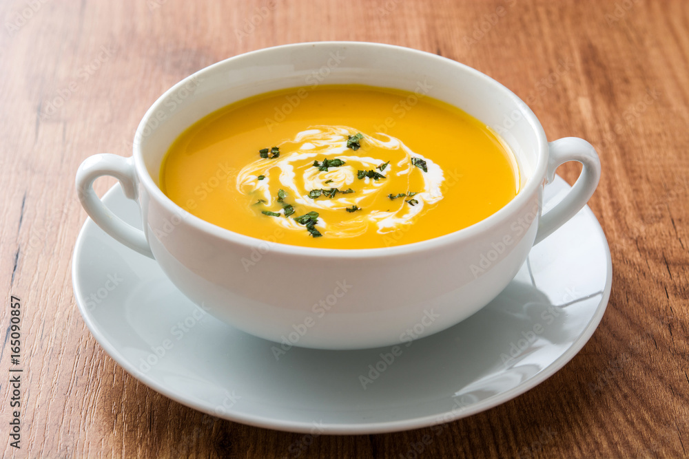 Pumpkin soup in white bowl on wooden table
Pumpkin soup in white bowl on wooden table