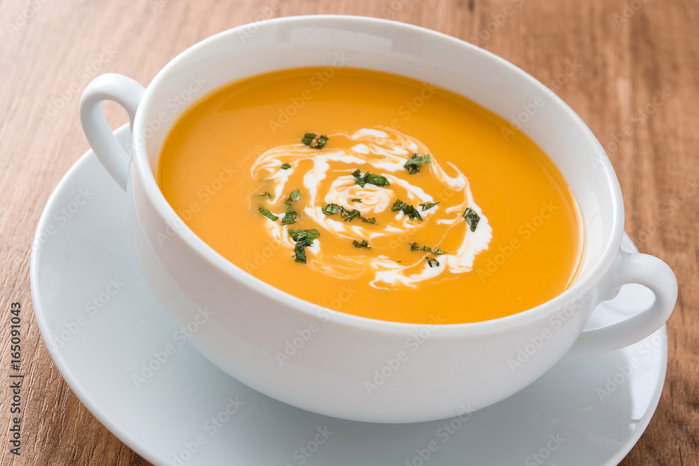 Pumpkin soup in white bowl on wooden table
Pumpkin soup in white bowl on wooden table