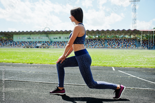 Portrait of an attractive fit woman doing exercises for her legs in the stadium.