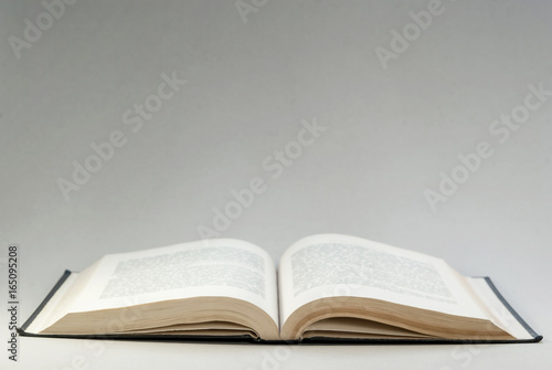 Disclosed book above on a gray background. Reading. Background for postcard, cover, textspace.