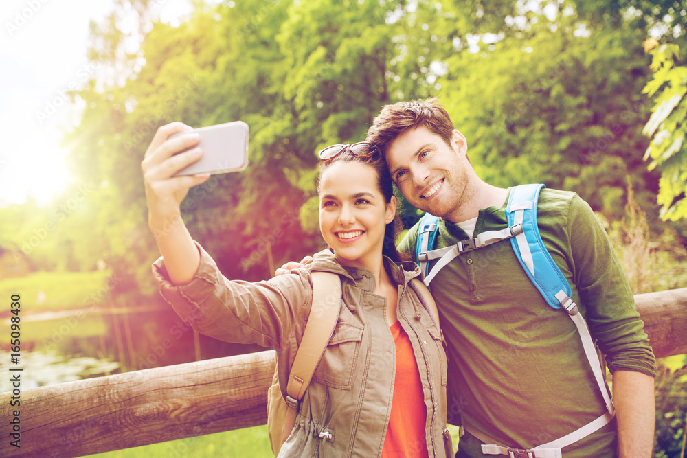 couple with backpacks taking selfie by smartphone couple with backpacks taking selfie by smartphone
