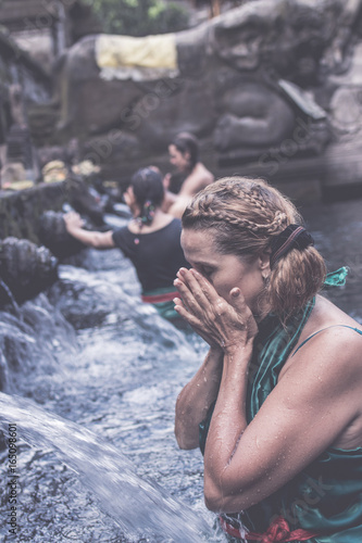 European woman at Pura Tirta Empul temple during a religious ceremony in Tampa  Bali  Indonesia.