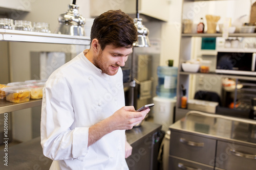 chef cook with smartphone at restaurant kitchen