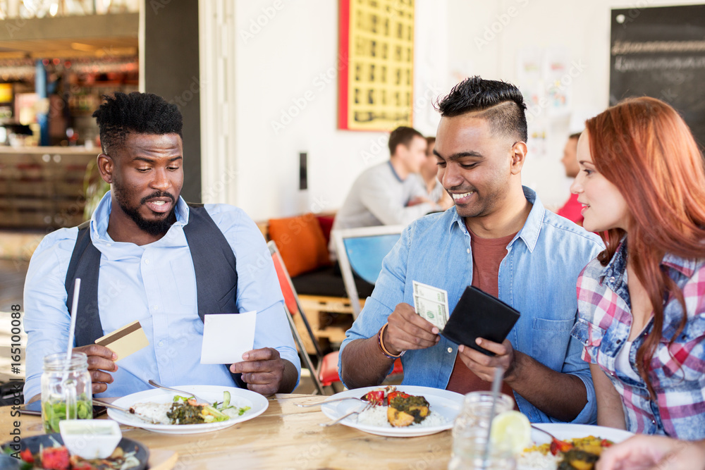 happy friends paying bill for food at restaurant