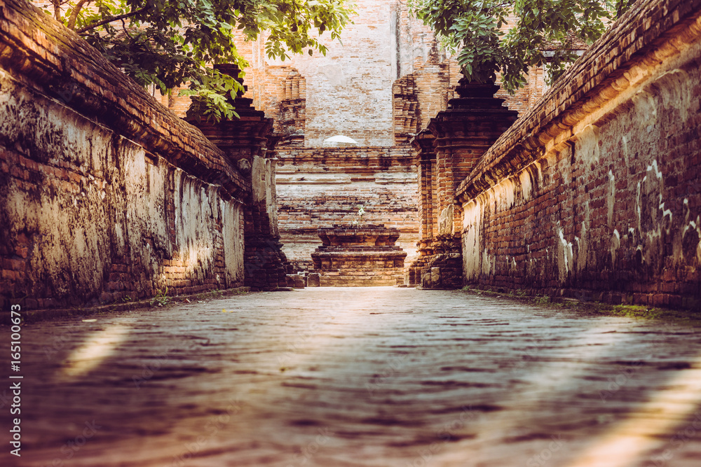 Walk way or entered to old chapel and pagoda with red brick wall of Wat Maheyong temple , Ayutthaya historical park Thailand. Vintage photo effect
