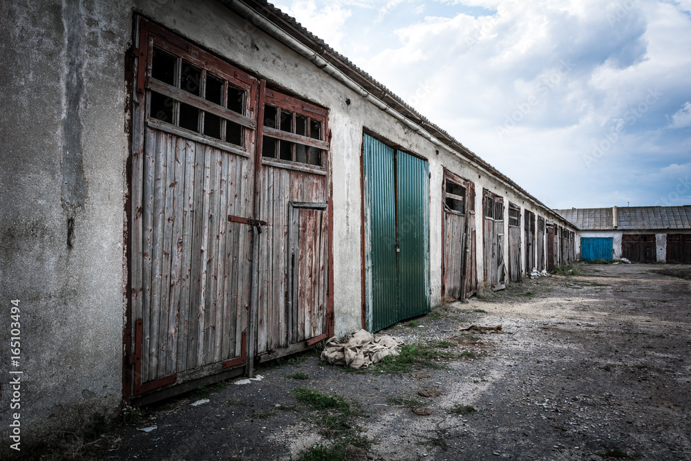 A dilapidated garage building against a cloudy evening sky A dilapidated garage building against a cloudy evening sky
