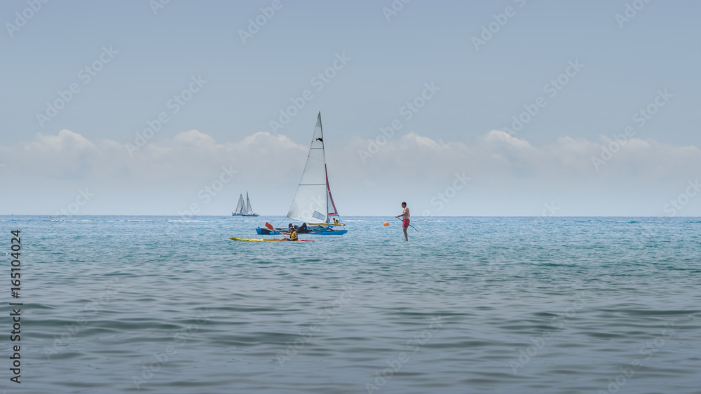 Naklejka premium Rest on sea. Sea kayak, boats with sail, stand up paddler. Outdoor sea sporting activity