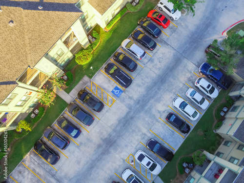 Aerial view of apartment garage with covered parking lots, cars and green trees at multi-floor buildings complex in Humble, Texas, US early morning. Urban infrastructure and transportation concept.