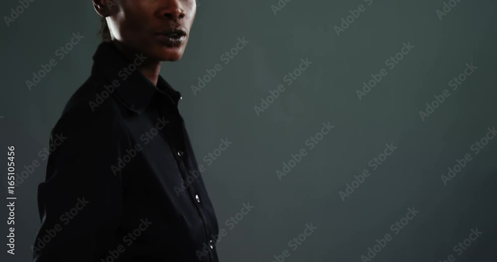 Androgynous man in suit posing against dark background Androgynous man in suit posing against dark background